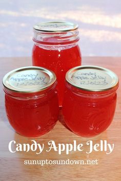 three jars filled with red liquid sitting on top of a wooden table