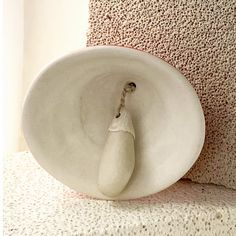 a white vase sitting on top of a floor next to a wall