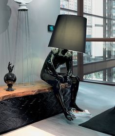 a lamp sitting on top of a wooden table next to a black and white statue