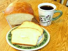 a loaf of bread sitting on top of a green and white plate next to a cup of coffee