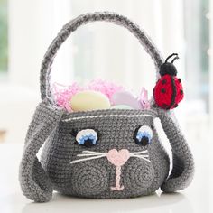 a gray crocheted basket with a ladybug on the front and side