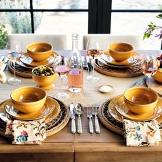 the table is set with yellow dishes and place settings for two people to sit at