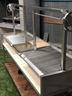 a metal conveyor belt sitting on top of a wooden floor next to a building