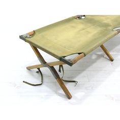 an old folding table with wooden legs and straps on the bottom, sitting on a white floor