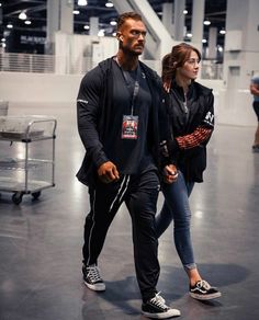 the man and woman are walking together in an empty building with their hands on each other's hips