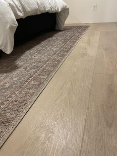 a bed sitting on top of a wooden floor next to a rug