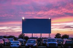 cars are parked in a parking lot with a large screen on the side of it