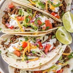 three tacos filled with ground beef, lettuce and tomatoes