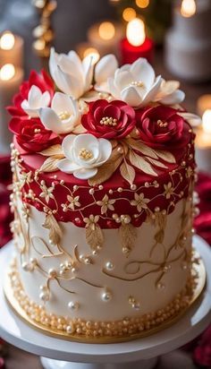 a red and white wedding cake with flowers on the top is sitting on a table