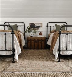 two metal beds sitting next to each other on top of a rug