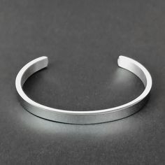 Embrace the Viking tradition of adornment with our Men's Silver Cuff Bracelet, a classic yet modern representation of Norse metalwork. Crafted from high-quality stainless steel, this bangle reflects the Viking passion for decoration in every aspect of life. Its sleek polished finish offers a contemporary twist to traditional Viking aesthetics, making it a perfect accessory for those who value both history and modern style. - Material: Stainless Steel - Rust, scratch and tarnish resistant; hypoal Minimalist Bangle With Stainless Steel Clasp, Minimalist Stainless Steel Jewelry With Brushed Finish, Classic Metal Cuff Bracelet, Classic Metal Cuff Bracelets, Modern Silver Metal Wristband, Classic Formal Stainless Steel Cuff Bracelet, Formal Stainless Steel Cuff Bracelet With Polished Finish, Classic Stainless Steel Wristband Bracelet, Modern Silver Wristband With Stainless Steel Clasp