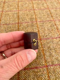 a hand holding a small wooden ring on top of a carpet