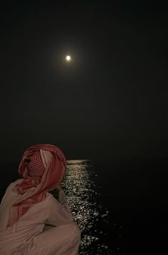 a person sitting on a boat looking at the moon