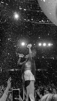 a black and white photo of a woman on stage with her arms in the air