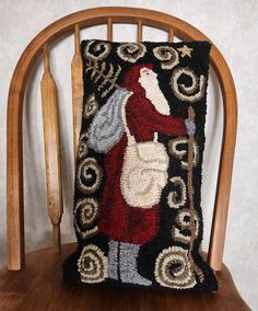 a decorative pillow on a wooden chair with a santa clause holding a sack and bag