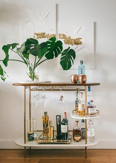 a bar cart filled with liquor bottles and glasses on top of a hard wood floor