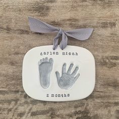 a ceramic plaque with two baby hands and one handprint on it