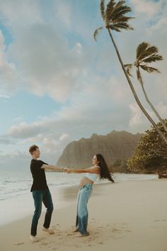 a man and woman holding hands on the beach with palm trees in the foreground