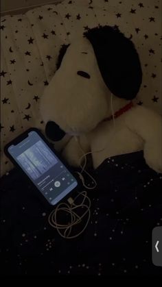 a stuffed dog laying on top of a bed next to an electronic device