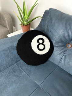 a black and white eight ball pillow sitting on top of a blue couch next to a potted plant