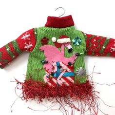 a green sweater with pink flamingos on it and red fringes around the neck