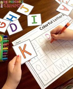 a child's hand is writing letters on a sheet of paper