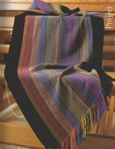 a multicolored blanket sitting on top of a wooden bench