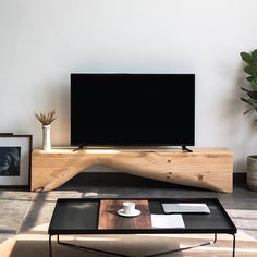 a living room with a coffee table, television and potted plant on the side