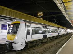 a white and yellow train pulling into the station