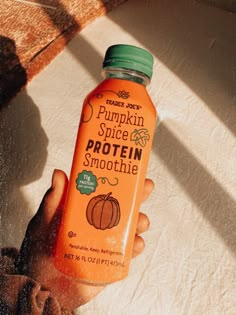 a hand holding a bottle of pumpkin spice protein smoothie