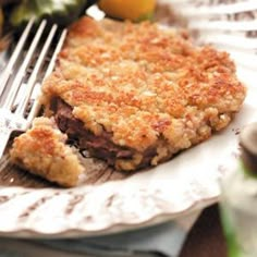 a piece of pie sitting on top of a white plate next to a knife and fork