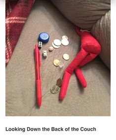 a red stuffed animal laying on top of a bed next to coins and a pen