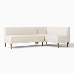 a white sectional sofa with wooden legs