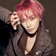 a young man with pink hair wearing a brown jacket and checkered blazer, posing for the camera