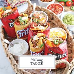 a basket filled with lots of tacos sitting on top of a table next to other foods