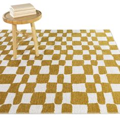 a yellow and white checkered rug with a small wooden table on the floor next to it