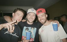 three men pose for the camera with cups in their hands