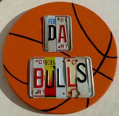 two license plates with the word bulls on them sitting next to an orange basketball ball