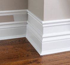 the corner of an empty room with wood flooring