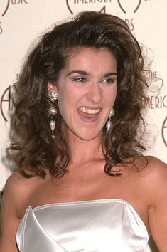 a woman in a silver dress smiling at the camera with her hand on her hip