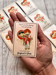 a person holding up some cards on top of a wooden table with other cards in front of them