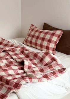 a red and white checkered blanket on top of a bed next to two pillows