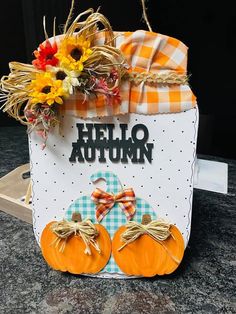 a hello autumn sign with pumpkins and sunflowers in it on a table