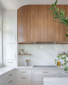 a kitchen with white cabinets and wood accents on the wall, along with marble counter tops