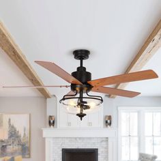 a ceiling fan with three wooden blades in a living room area next to a fireplace