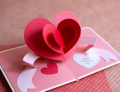 a folded heart on top of a pink card