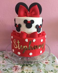 a minnie mouse cake with red bow and name on top, sitting on a table