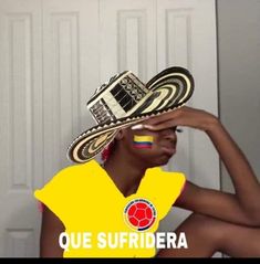 a woman in a yellow shirt is holding a hat over her head with the words que sufridera on it