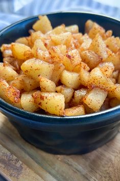 a blue bowl filled with cooked potatoes on top of a wooden cutting board