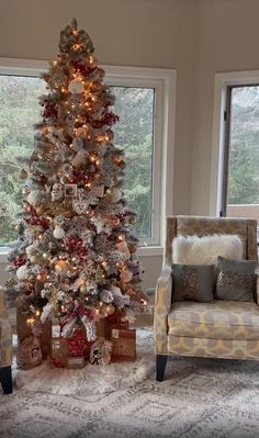 a living room with a christmas tree and two chairs in front of the window,